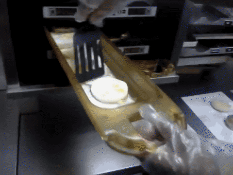 A McDonalds worker retrieving egg discs from a heater machine